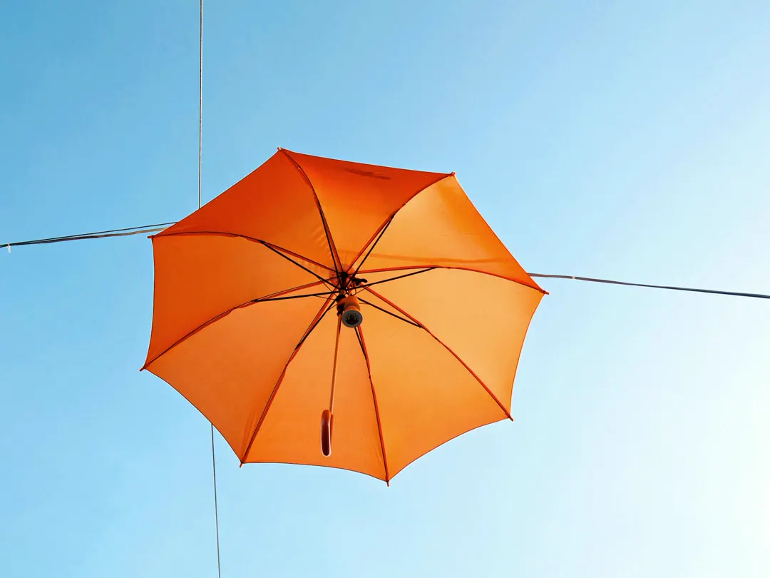 An orange umbrella against a blue sky