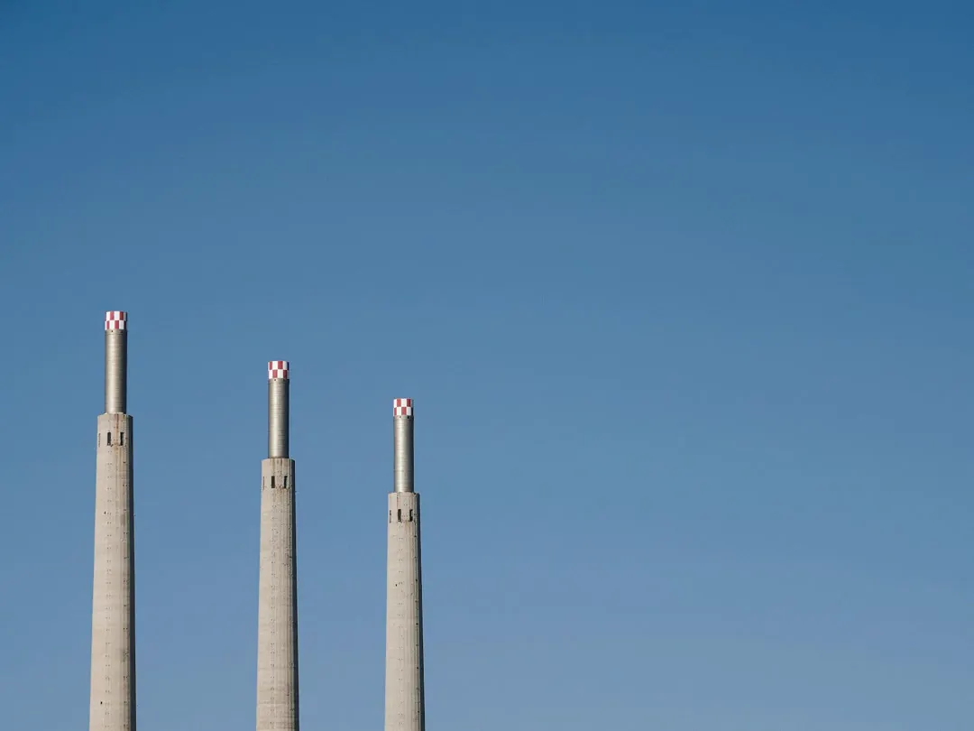 Three factory chimneys against a blue sky