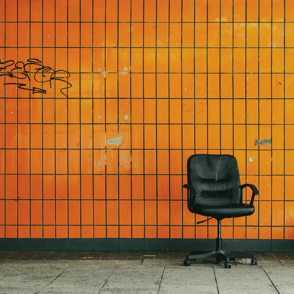 An empty office chair against an orange tiled wall